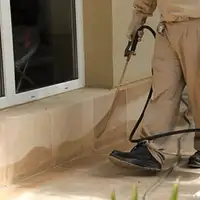 General pest control technician spraying exterior perimeter around a home in Provo, UT