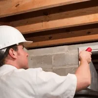 Termite inspection technician checking a basement wall and framing for termite activity in Provo, UT
